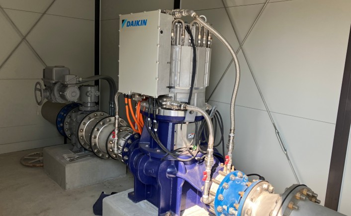 建屋内に設置されたDAIKINブランドのマイクロ水力発電機(小水力発電機)。配管に直結された縦形ポンプ逆転水車の近接写真