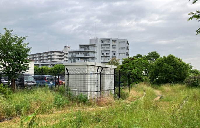 フェンスで囲まれた屋外の敷地にコンパクトに設置されている、マイクロ水力発電システム用のグレーのシステム制御盤2台