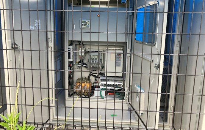 扉が開いた屋外システム制御盤の内部。リアルタイム監視用のタッチパネルモニターや精密な制御基板・配線が収まっている様子