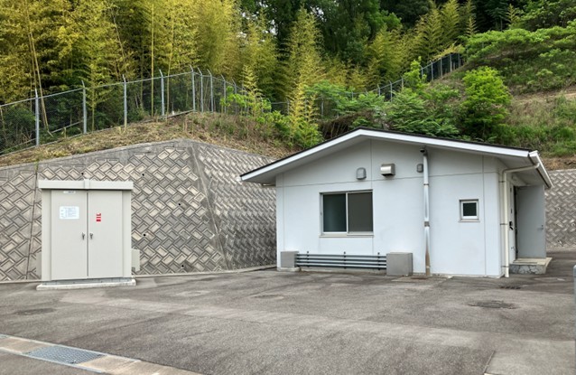 黒瀬調整池マイクロ水力発電所の施設外観。敷地左側に制御用キュービクル、右側に発電機が設置されている白壁の流入弁室建屋