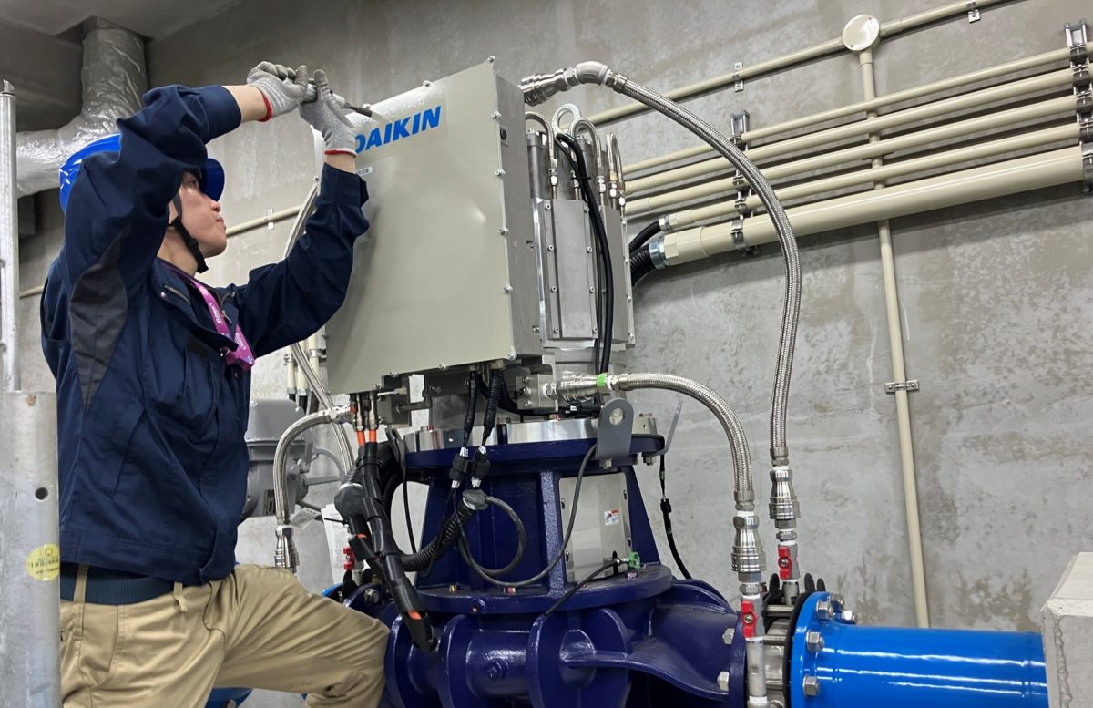 ダイキンロゴの入った縦型マイクロ水力発電機の構造点検および工具を用いた定期メンテナンス風景