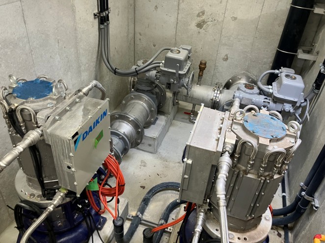 吹田市津雲配水場の地下ピット内における、並列配置されたマイクロ水力発電機およびバルブ・制御配線の近接写真